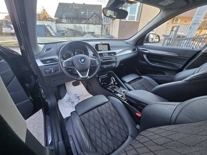 Slika prikazuje unutrašnjost vozila — kokpit, sjedala i volan.