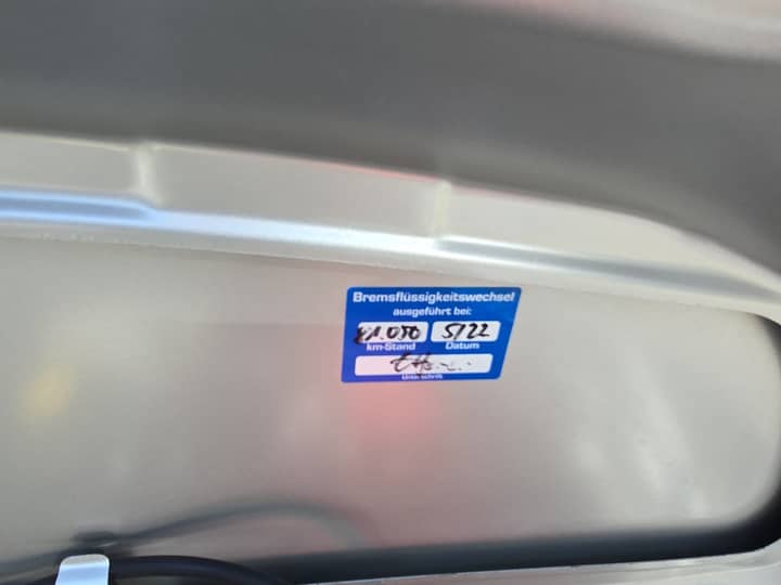 Slika prikazuje unutrašnjost vozila s oznakom na panelu.