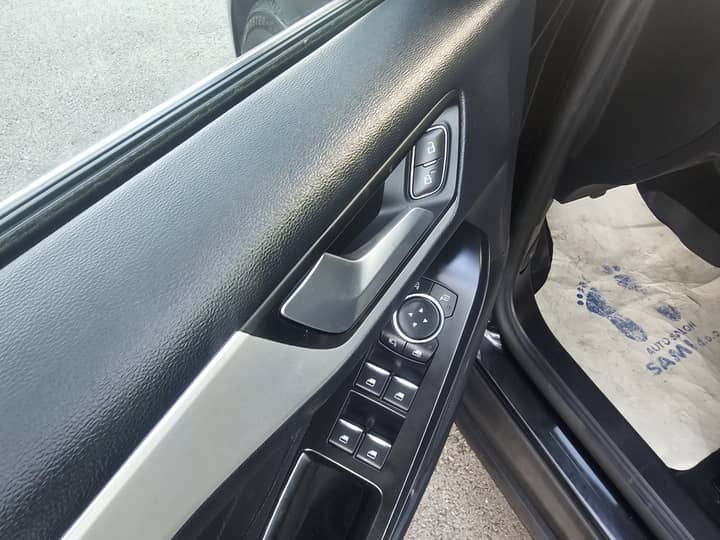 Slika prikazuje unutrašnjost vozila, panel vrata i kontrole.