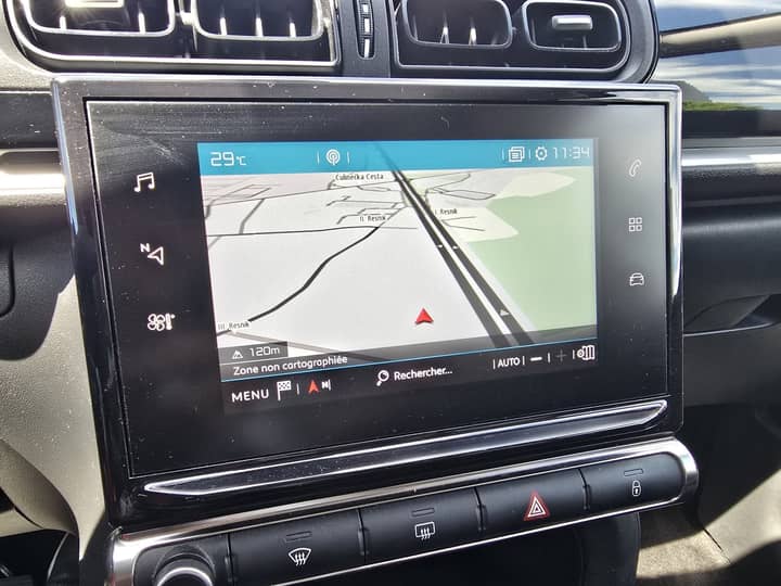 Slika prikazuje unutrašnjost vozila s infotainment sustavom.