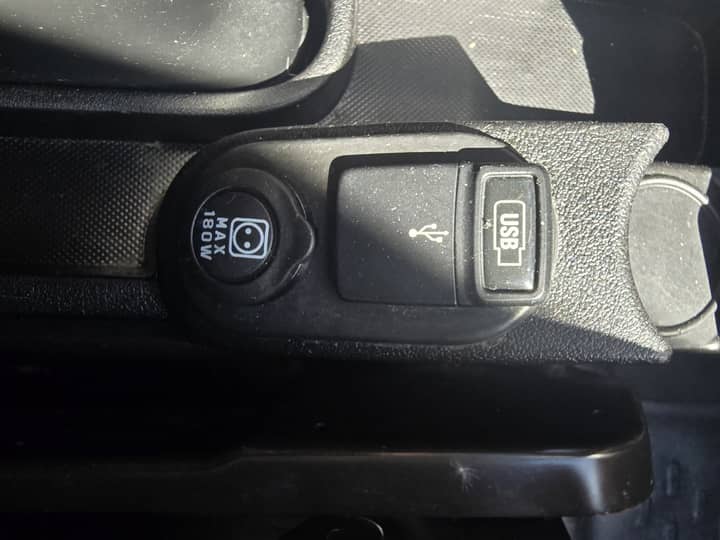 Slika prikazuje unutrašnjost vozila: utičnica i USB priključak.