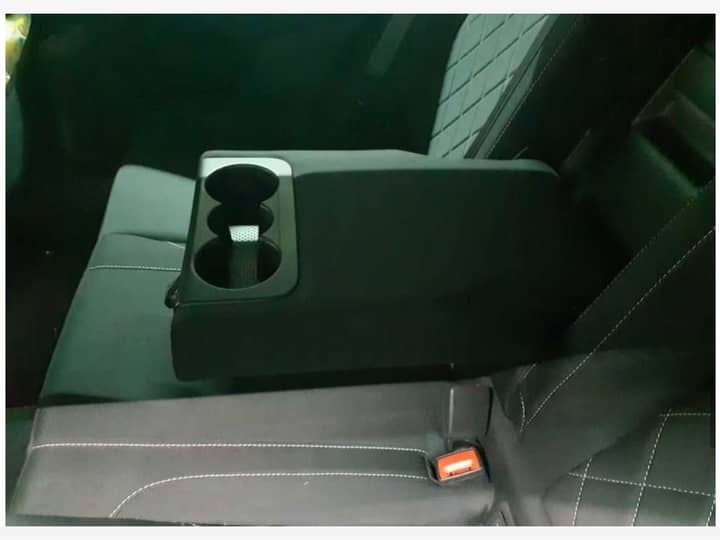 Slika prikazuje unutrašnjost vozila, središnji armrest i držač za piće.