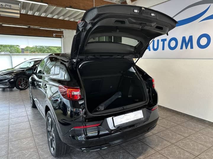 Slika prikazuje vanjštinu automobila s otvorenim prtljažnikom.