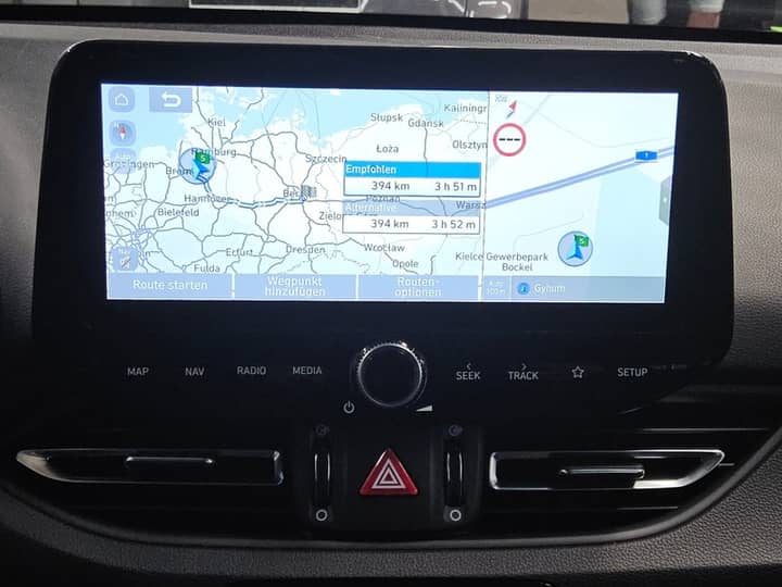 Slika prikazuje unutrašnjost vozila s navigacijskim zaslonom.