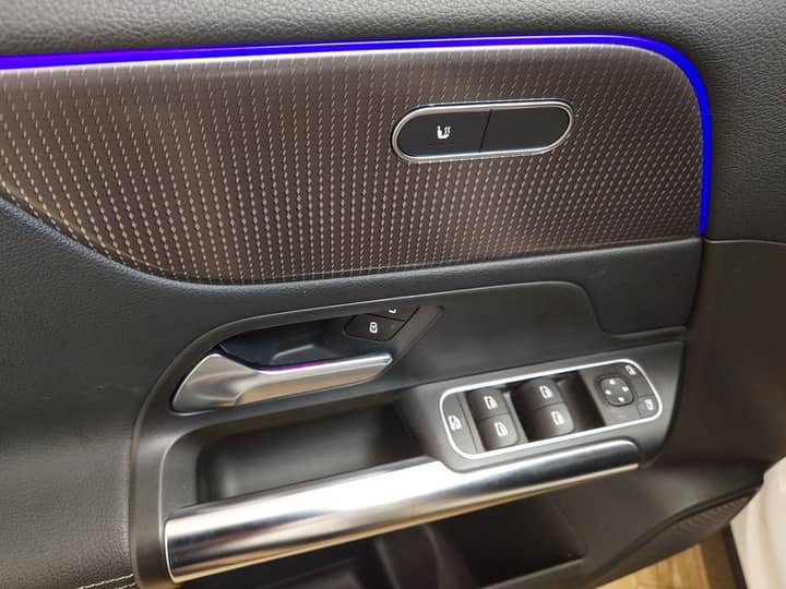 Slika prikazuje unutrašnjost vozila: panel vrata i kontrole.