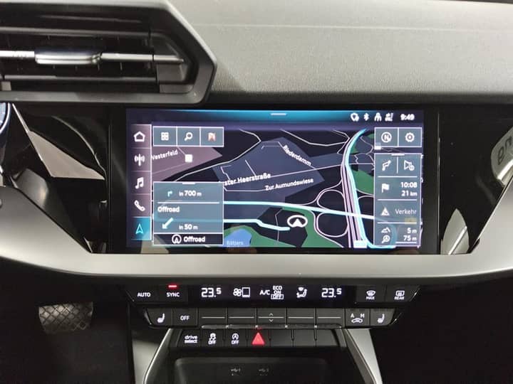 Unutrašnjost vozila s usmjerenim zaslonom za navigaciju i centra konzolom vidljiva iza središnje dash obloge.