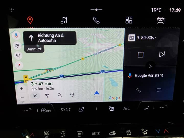 Slika prikazuje unutrašnjost vozila s infotainment zaslonom.
