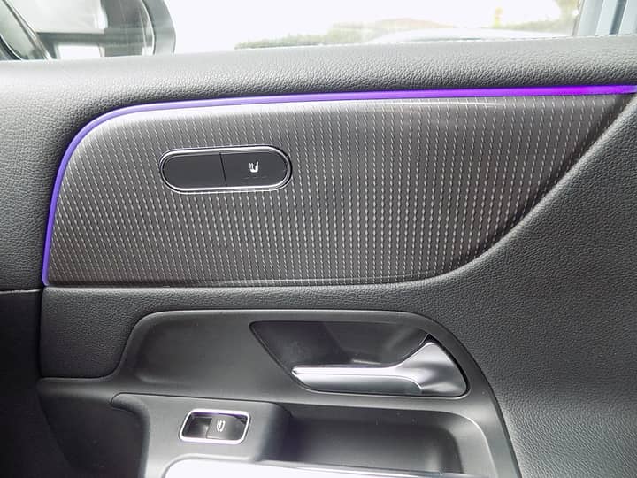 Slika prikazuje unutrašnjost vozila, panel vrata i prekidače.