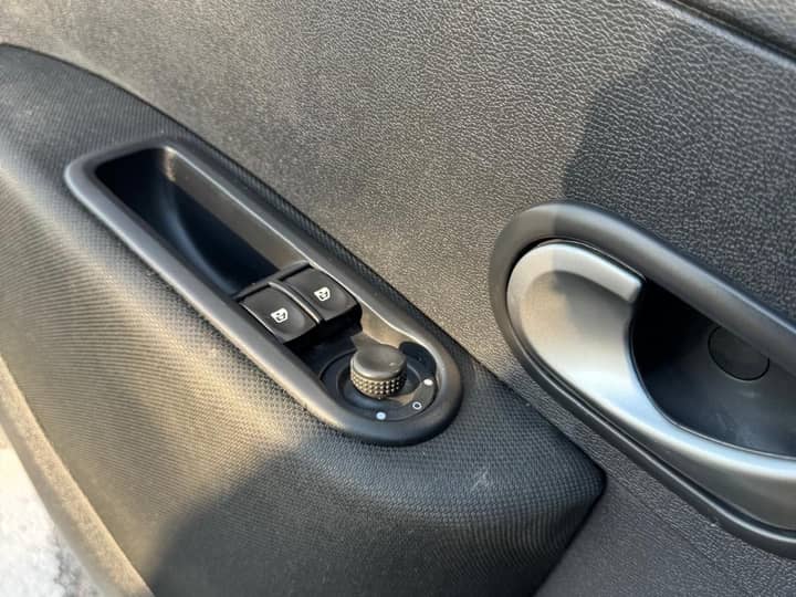 Slika prikazuje unutrašnjost vozila panel vrata i kontrole.
