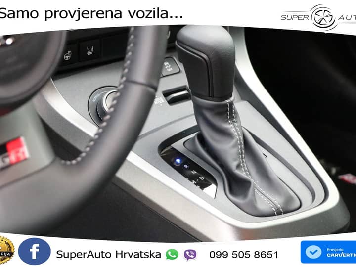 Slika prikazuje unutrašnjost vozila: ručica mjenjača i konzolu.