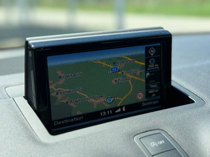 Slika prikazuje unutrašnjost vozila s navigacijskim zaslonom.