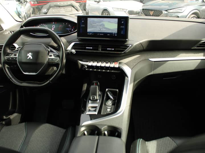 Slika prikazuje unutrašnjost vozila — volan, središnja ploča i sjedala.