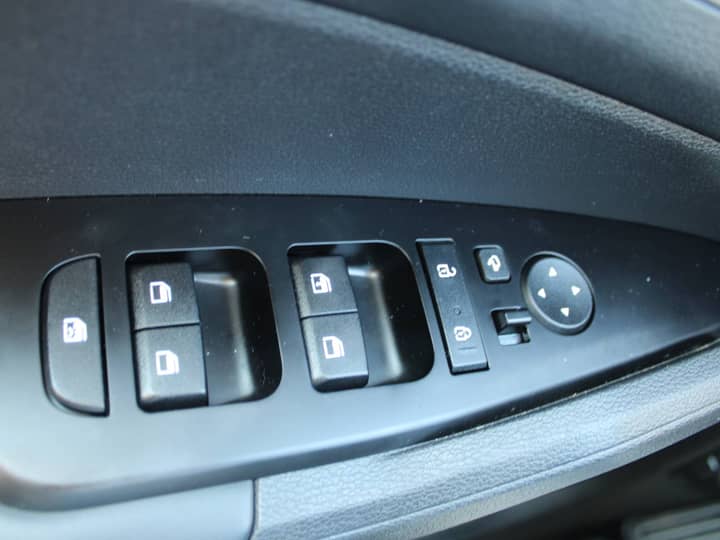 Slika prikazuje unutrašnjost vozila, panel s gumbima za prozore.