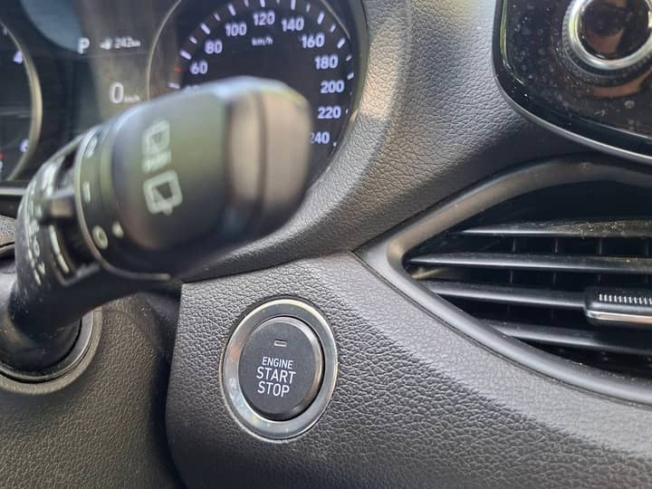 Slika prikazuje unutrašnjost vozila: volan, instrument ploča i start/stop gumb.