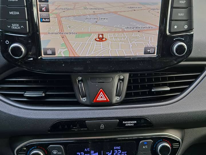 Slika prikazuje unutrašnjost vozila s navigacijskim zaslonom.