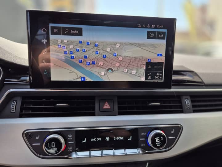 Slika prikazuje unutrašnjost vozila s navigacijskim zaslonom.
